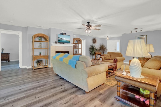 living room featuring track lighting, a tiled fireplace, ceiling fan, and hardwood / wood-style floors