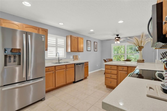 kitchen with light stone countertops, stainless steel appliances, sink, light tile floors, and ceiling fan