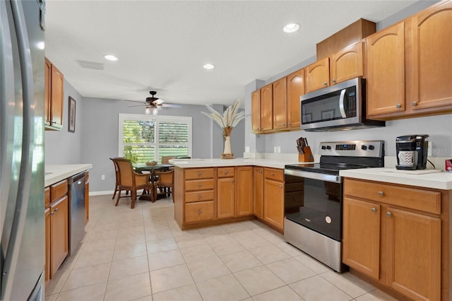 kitchen with appliances with stainless steel finishes, ceiling fan, kitchen peninsula, and light tile floors