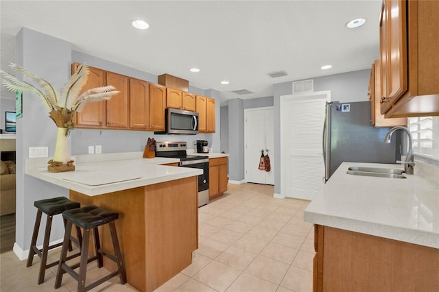 kitchen featuring kitchen peninsula, a breakfast bar area, stainless steel appliances, sink, and light tile floors