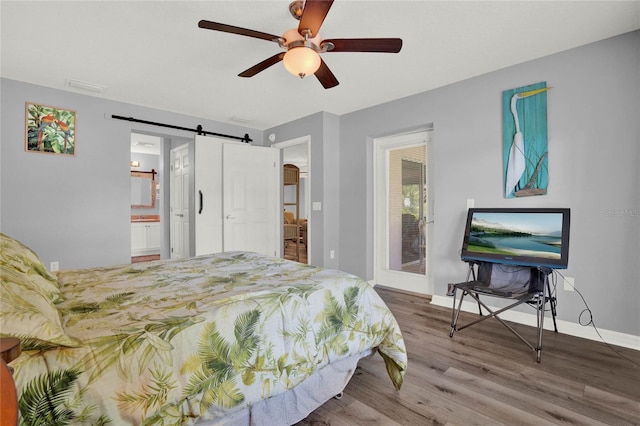 bedroom featuring wood-type flooring, ceiling fan, connected bathroom, and a barn door