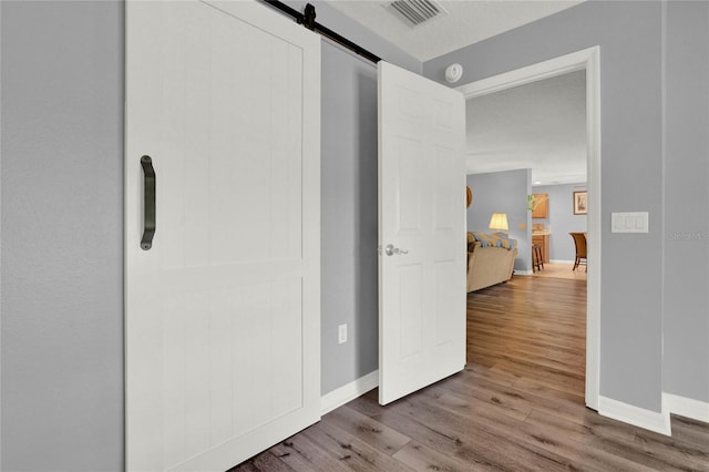 hallway featuring a textured ceiling, hardwood / wood-style flooring, and a barn door