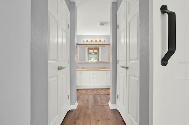 hallway featuring wood-type flooring, sink, and a textured ceiling