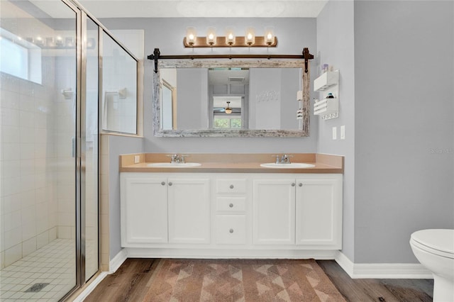 bathroom featuring hardwood / wood-style flooring, a shower with door, toilet, and double sink vanity