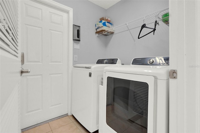 laundry room featuring light tile floors and washer and clothes dryer