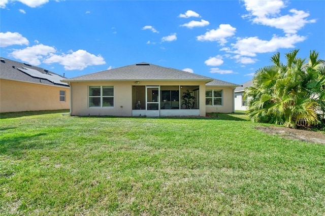 rear view of property featuring a yard, solar panels, and a sunroom