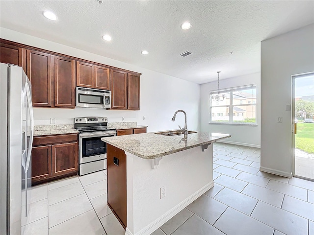 kitchen with sink, stainless steel appliances, a center island with sink, and light tile patterned flooring