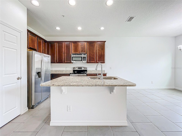 kitchen with light tile patterned floors, appliances with stainless steel finishes, sink, and light stone counters