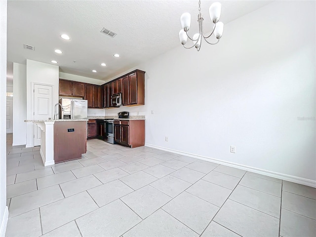 kitchen with appliances with stainless steel finishes, a chandelier, a kitchen island with sink, light tile patterned flooring, and hanging light fixtures