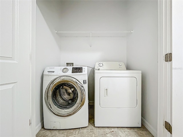 clothes washing area with washing machine and dryer and light tile patterned floors