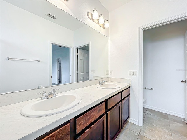 bathroom featuring tile patterned floors, double sink vanity, and toilet