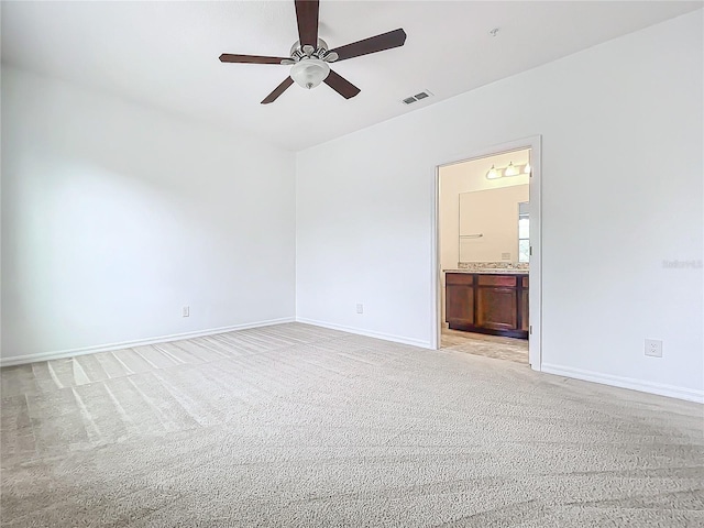 unfurnished bedroom with ceiling fan, light colored carpet, and ensuite bathroom