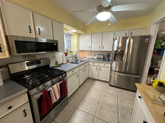 kitchen with stainless steel appliances, backsplash, light tile floors, sink, and white cabinetry