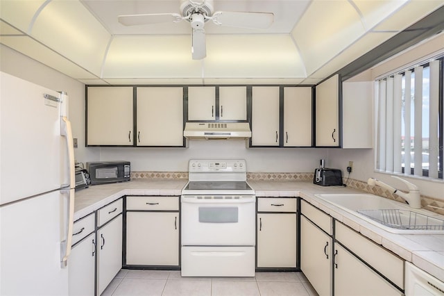 kitchen with white appliances, ceiling fan, light tile floors, and tile countertops