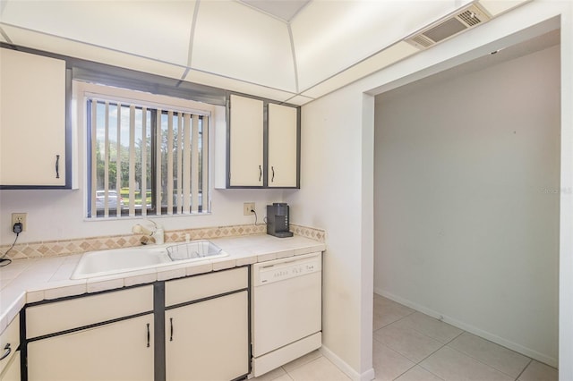 kitchen with light tile floors, dishwasher, tile counters, and sink