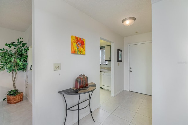 corridor with a textured ceiling and light tile flooring