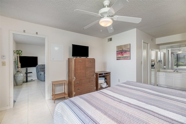 bedroom featuring a textured ceiling, ceiling fan, light tile floors, and ensuite bathroom