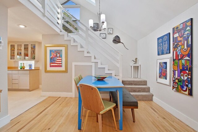 dining area featuring a chandelier, light hardwood / wood-style floors, and high vaulted ceiling