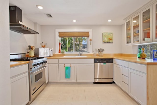 kitchen featuring white cabinets, wall chimney range hood, and stainless steel appliances