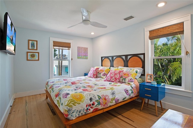 bedroom featuring light wood-type flooring, multiple windows, and ceiling fan