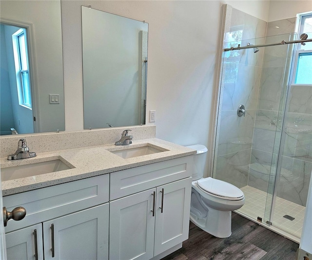 bathroom with double vanity, wood-type flooring, an enclosed shower, and toilet