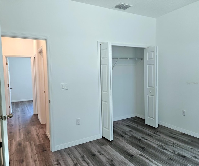 unfurnished bedroom featuring a closet and dark hardwood / wood-style floors