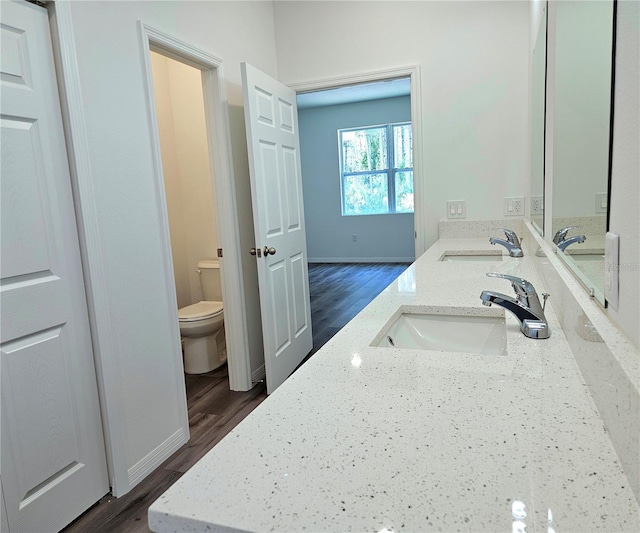 bathroom with hardwood / wood-style flooring, toilet, and dual vanity