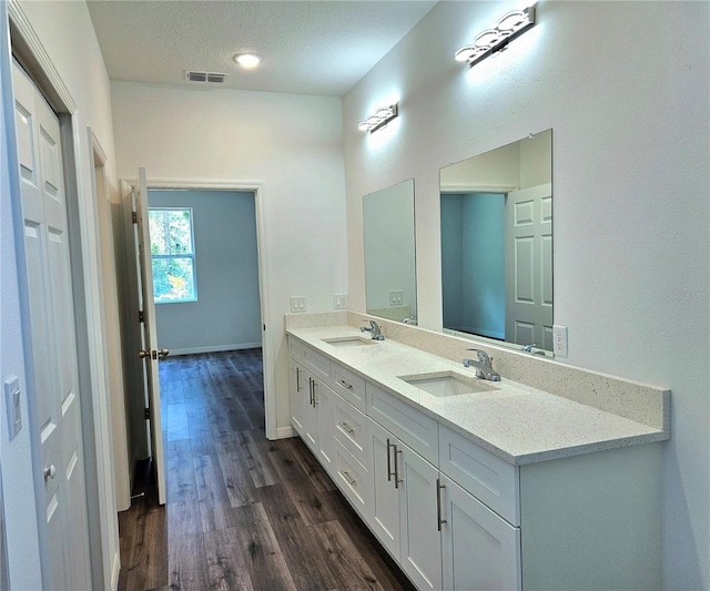 bathroom with double sink vanity, hardwood / wood-style flooring, and a textured ceiling