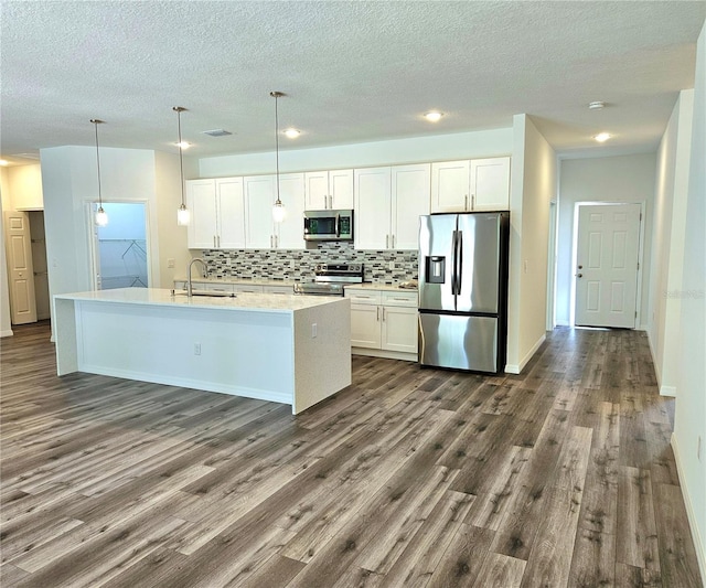 kitchen with white cabinets, hardwood / wood-style floors, stainless steel appliances, and decorative light fixtures