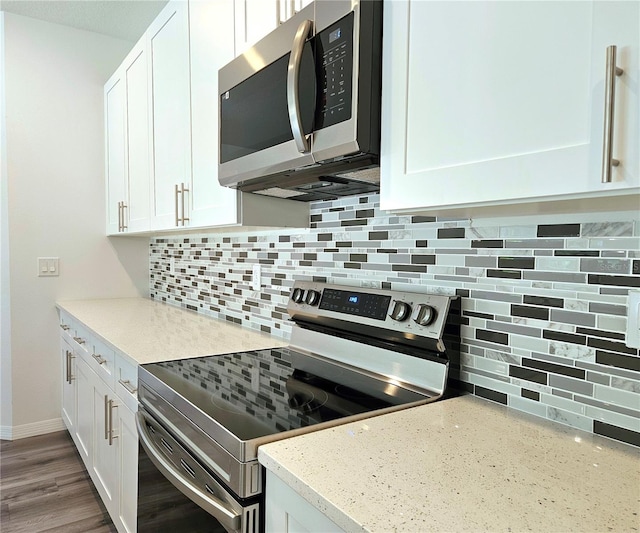 kitchen with hardwood / wood-style floors, backsplash, white cabinets, and stainless steel appliances