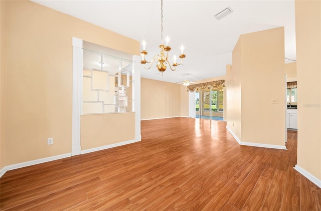 empty room with a notable chandelier and hardwood / wood-style floors