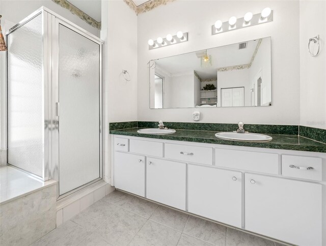 bathroom with a shower with shower door, dual vanity, and tile floors