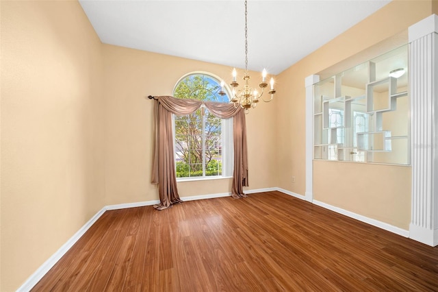 unfurnished room featuring an inviting chandelier and hardwood / wood-style floors