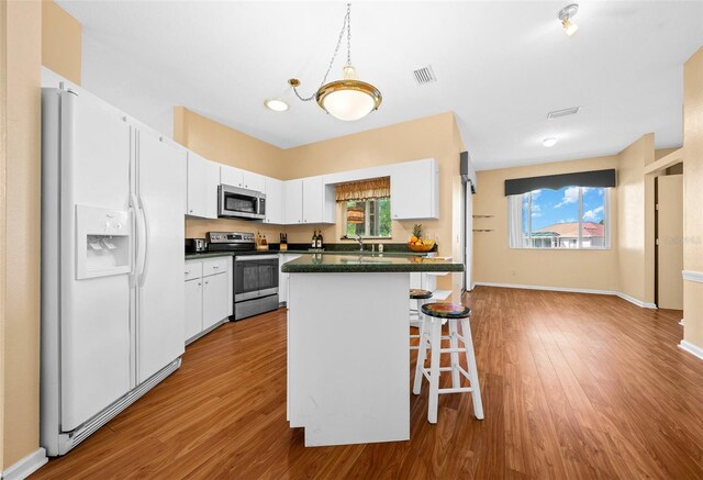 kitchen with stainless steel appliances, light hardwood / wood-style floors, white cabinetry, and a wealth of natural light