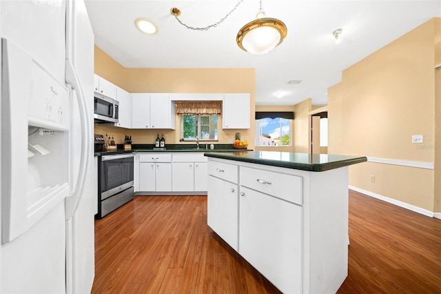 kitchen featuring stainless steel appliances, white cabinets, sink, and wood-type flooring