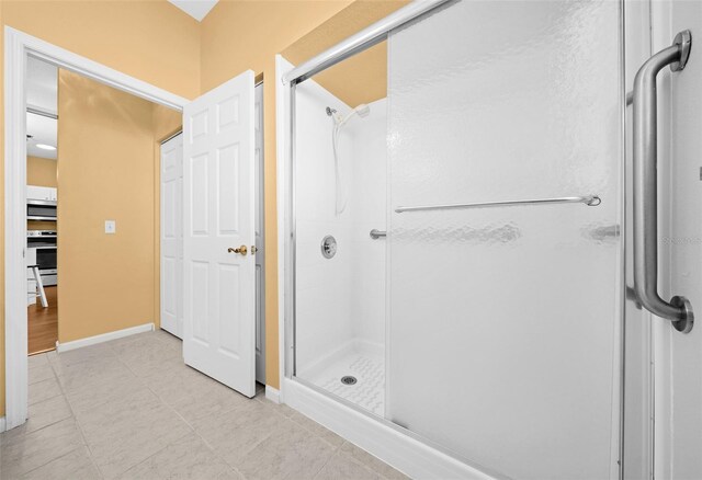 bathroom featuring a shower with door and tile flooring