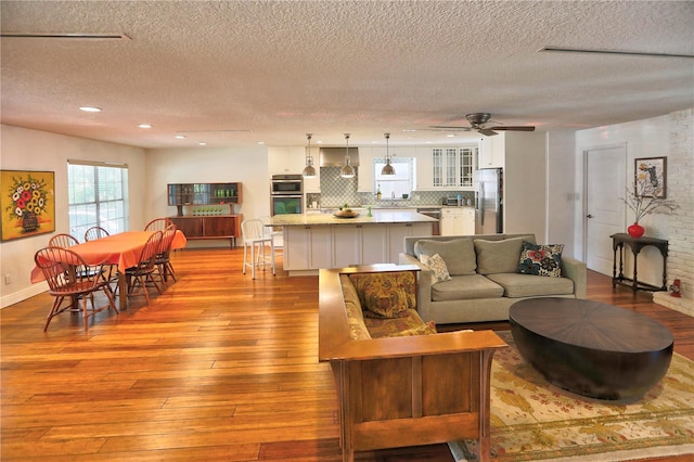 living room featuring a textured ceiling, ceiling fan, and light hardwood / wood-style flooring