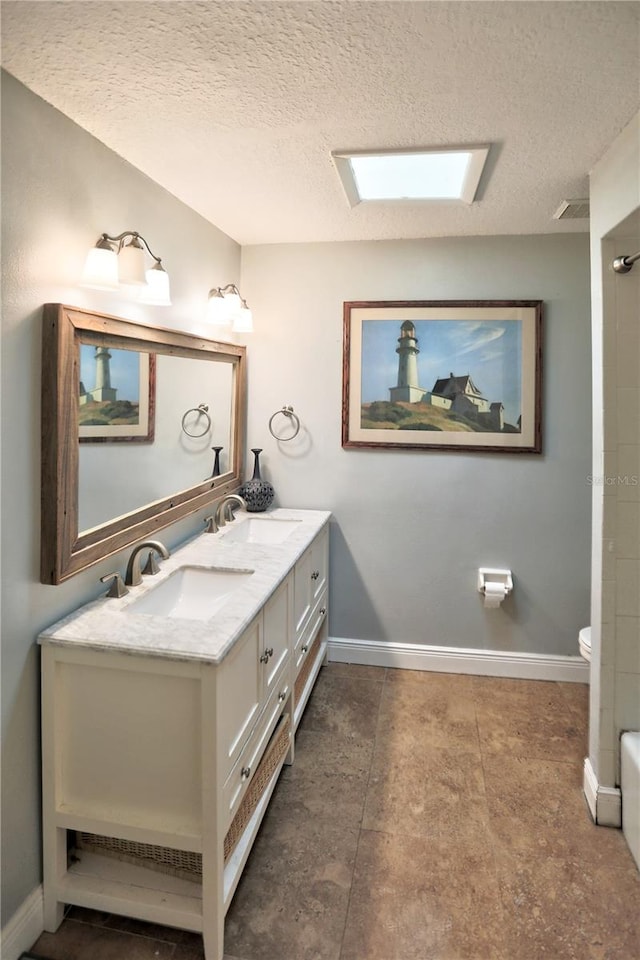 bathroom featuring vanity, toilet, and a textured ceiling