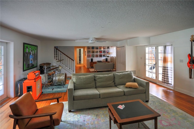 living room with ceiling fan, light hardwood / wood-style floors, and a textured ceiling