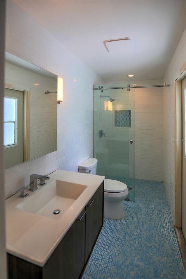 bathroom featuring tile patterned flooring, tile walls, an enclosed shower, vanity, and toilet