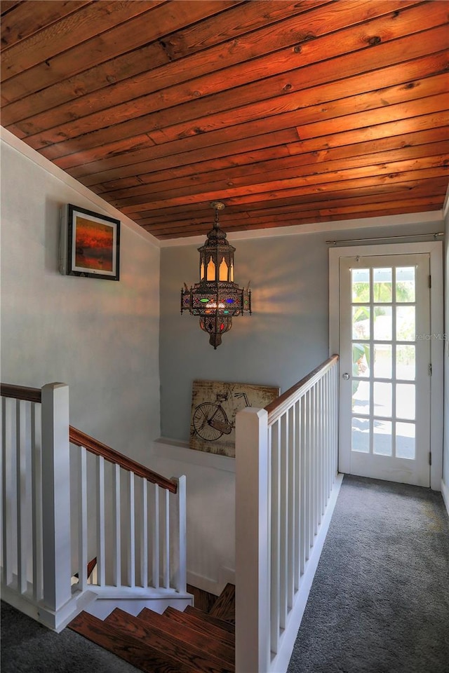 stairs featuring lofted ceiling, an inviting chandelier, wooden ceiling, and carpet