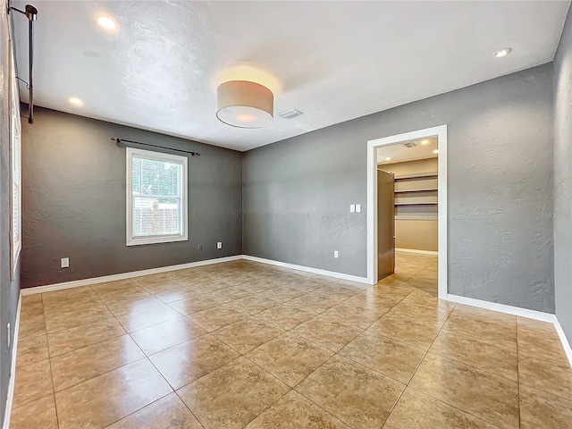 unfurnished bedroom with a walk in closet, light tile patterned floors, and a closet