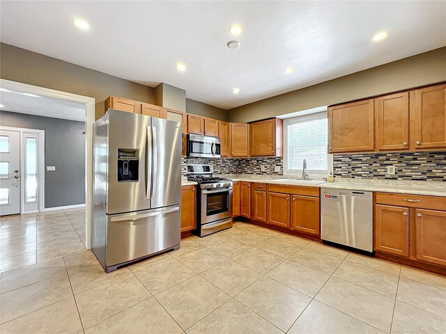 kitchen featuring decorative backsplash, appliances with stainless steel finishes, light tile patterned floors, and sink