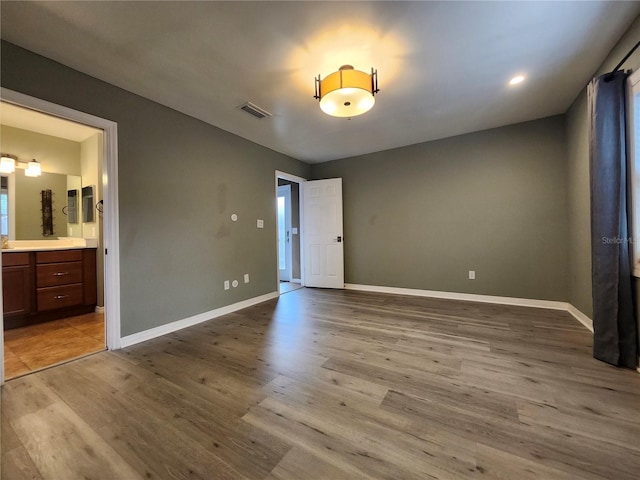 unfurnished bedroom featuring light hardwood / wood-style floors and ensuite bath