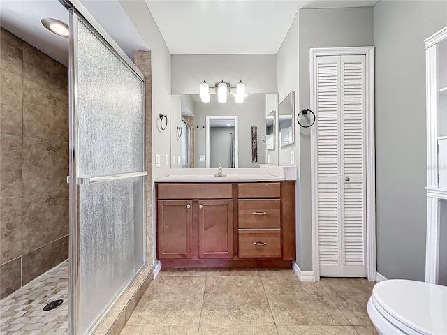 bathroom with tile patterned flooring, a shower with door, vanity, and toilet