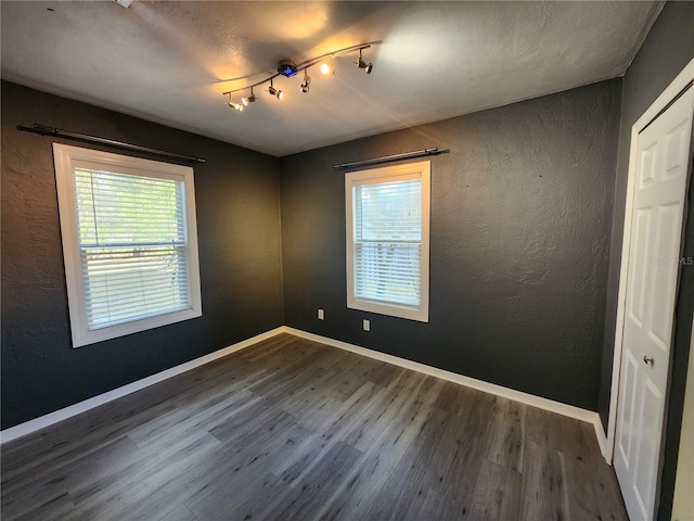 spare room with rail lighting and dark hardwood / wood-style floors