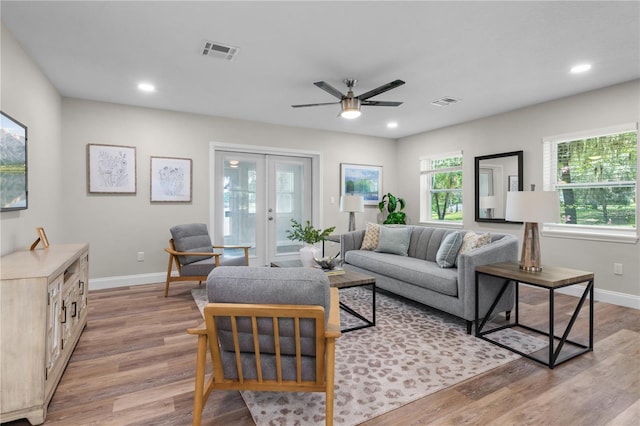 living room featuring light wood-style floors, baseboards, visible vents, and french doors