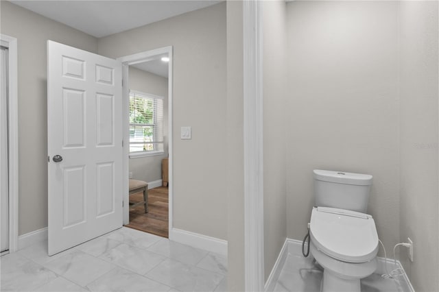 bathroom featuring marble finish floor, toilet, and baseboards