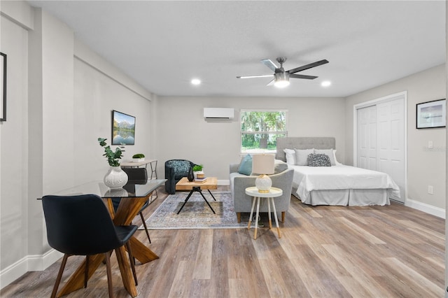 bedroom with ceiling fan, recessed lighting, wood finished floors, baseboards, and a wall mounted AC