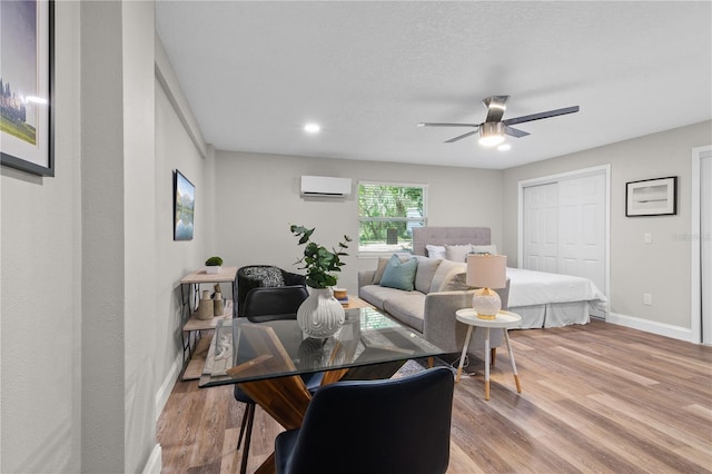 bedroom with light wood-type flooring, a closet, a wall unit AC, and baseboards